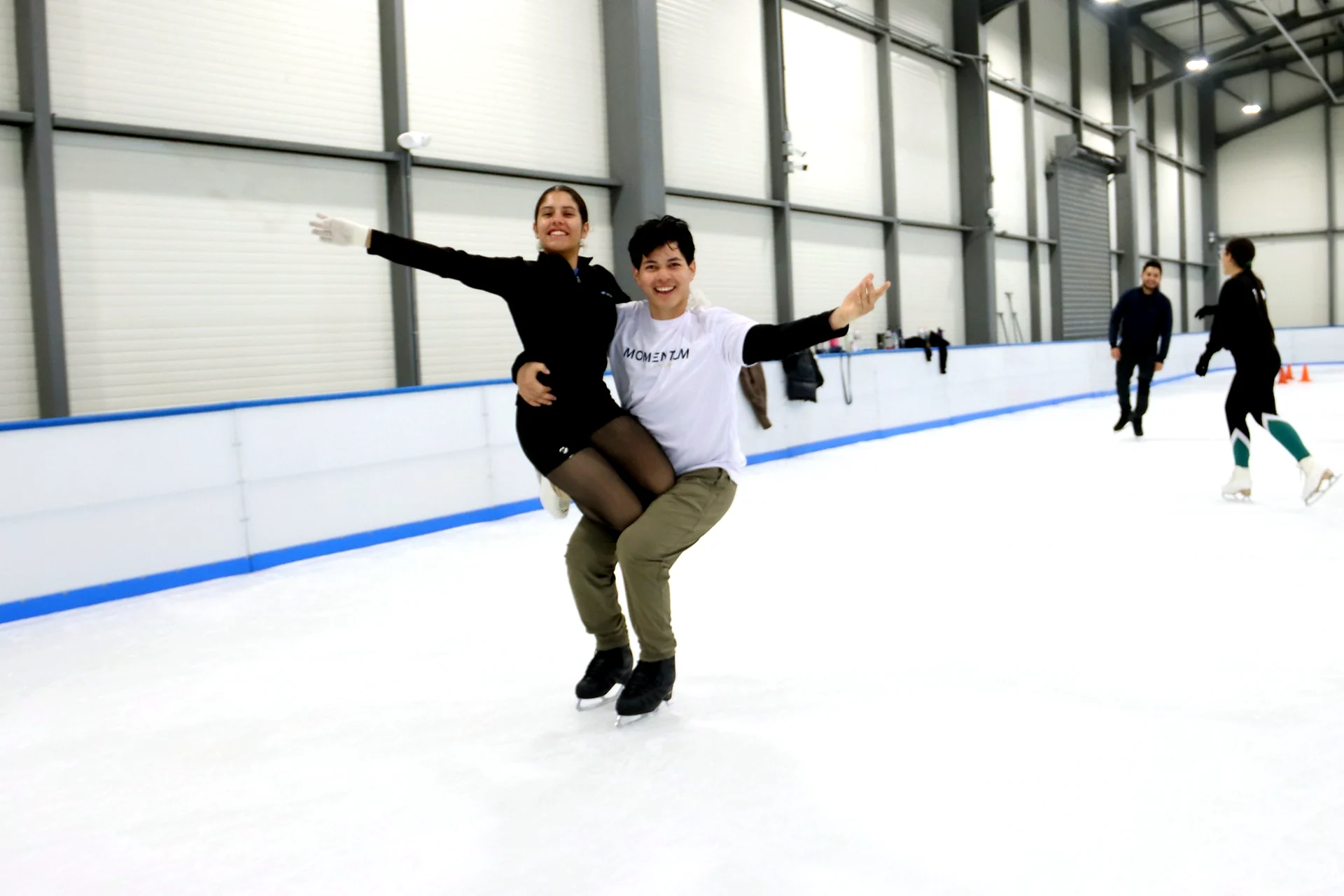 Dos integrantes de Ice Gravity sonriendo y posando juntos sobre la pista de hielo
