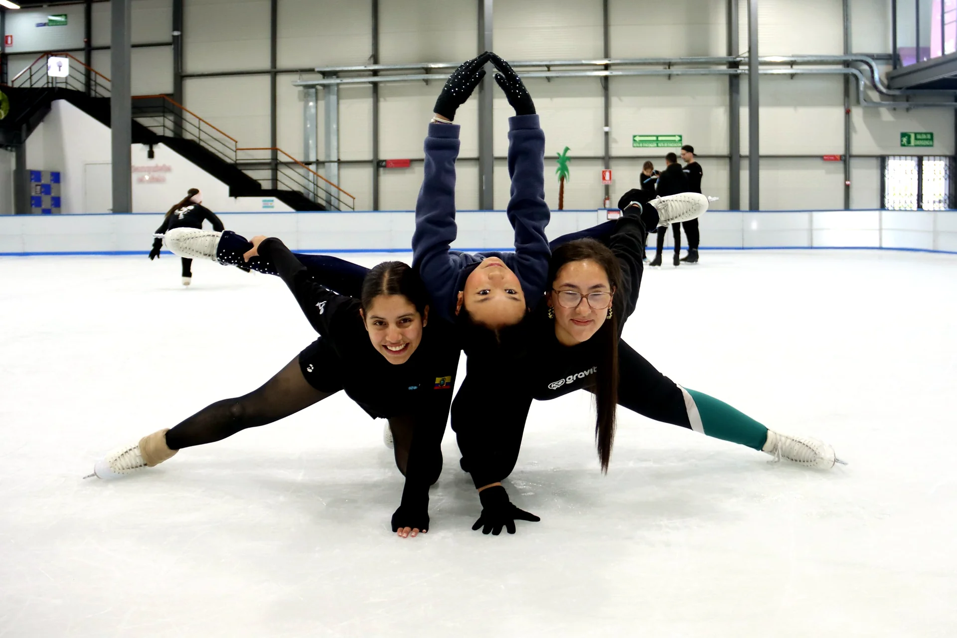 Tres estudiantes de Ice Gravity posando felices sobre la pista de hielo
